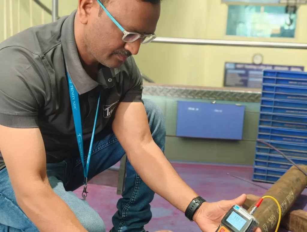 Trinity NDT engineer performing portable Leeb hardness testing on a steel rod and bar forging at the NDT laboratory in Bangalore
